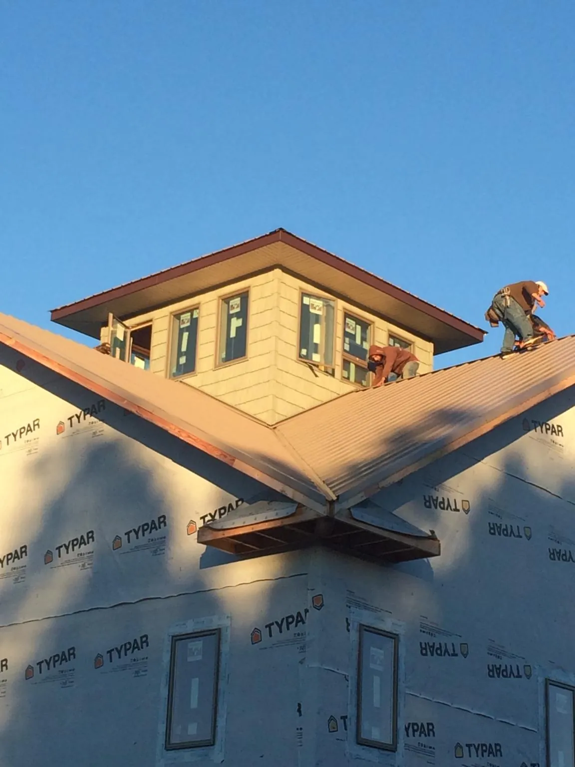 Roofers working around a rooftop cupola on a new metal roof at sunset — Roof Waterproofing in Pleasanton by Roofing Brothers
